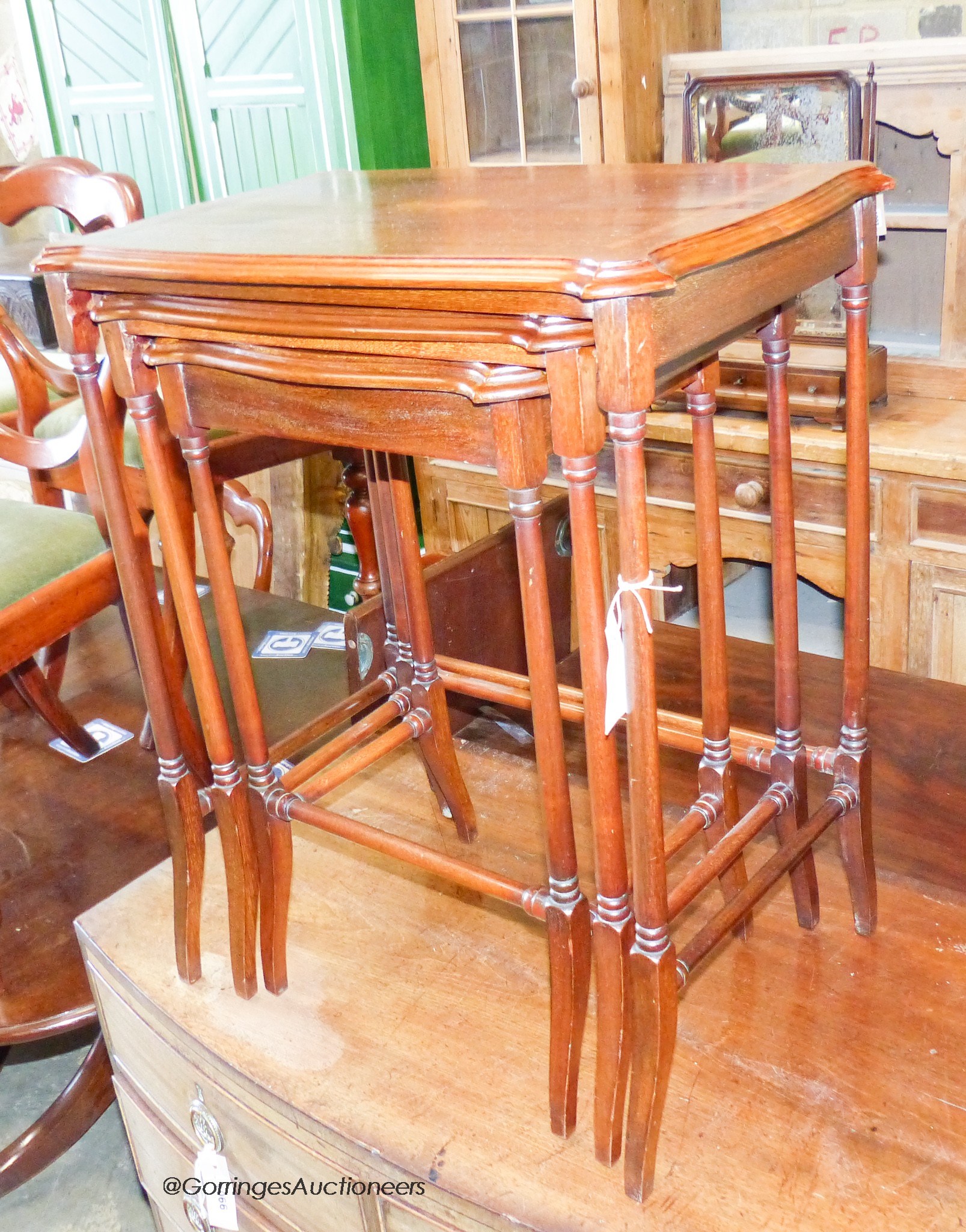 A nest of three Edwardian style inlaid mahogany serpentine tea tables, width 55cm, depth 35cm, height 66cm